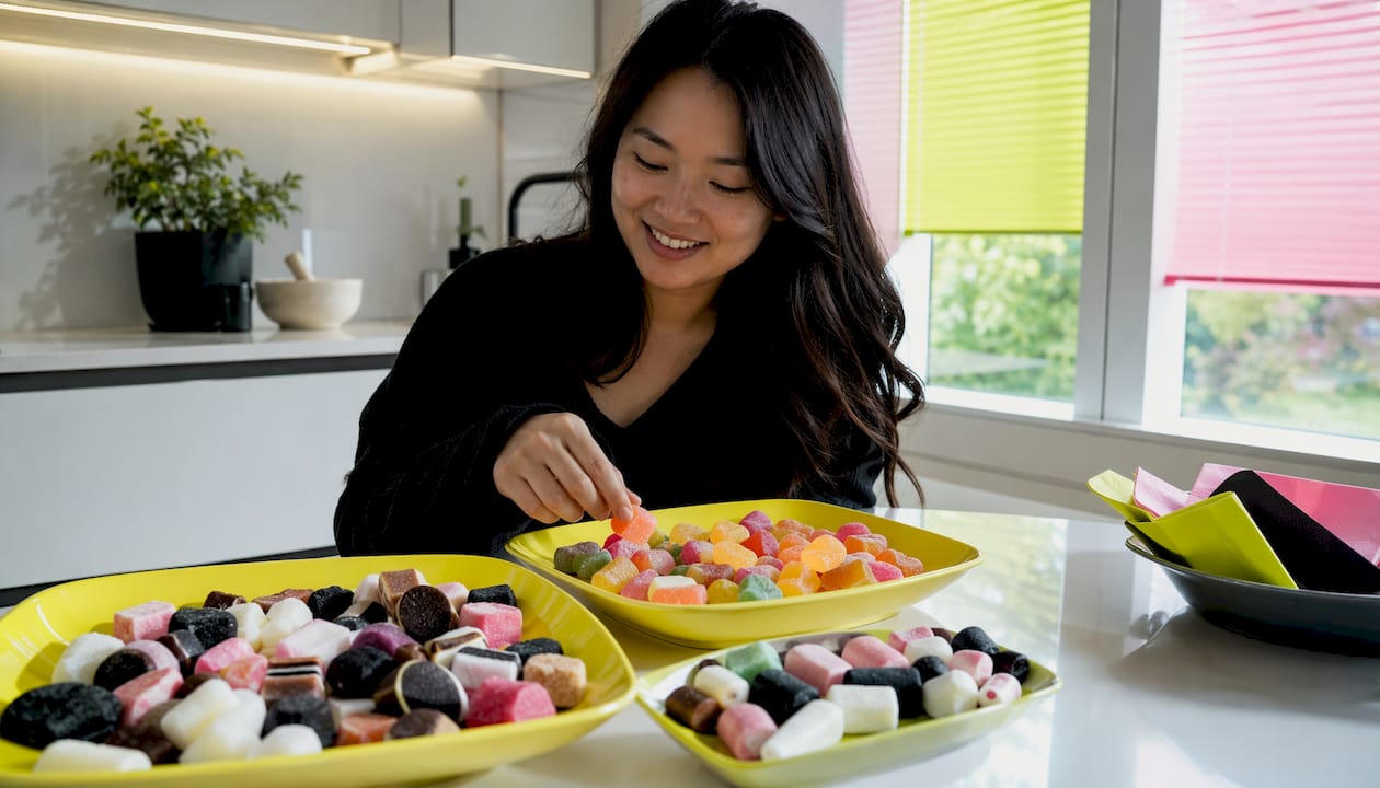 Woman tasting assorted Swedish candies at kitchen table