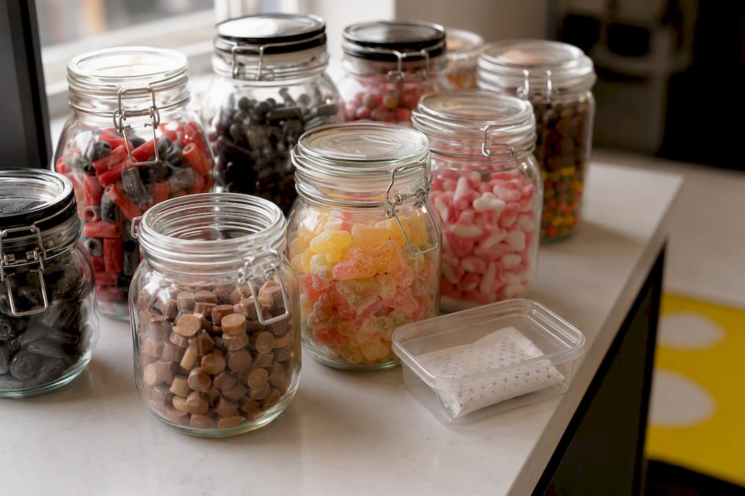 Glass jars with assorted candies on kitchen shelf