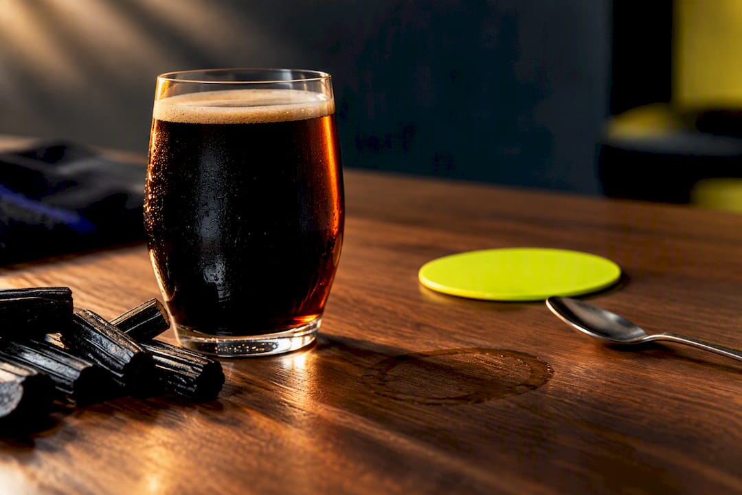 Dark beer beside black licorice pieces