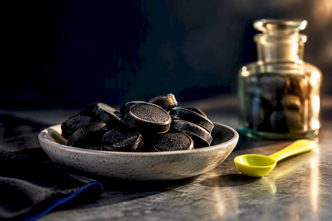 Dark salty licorice pastilles in ceramic dish